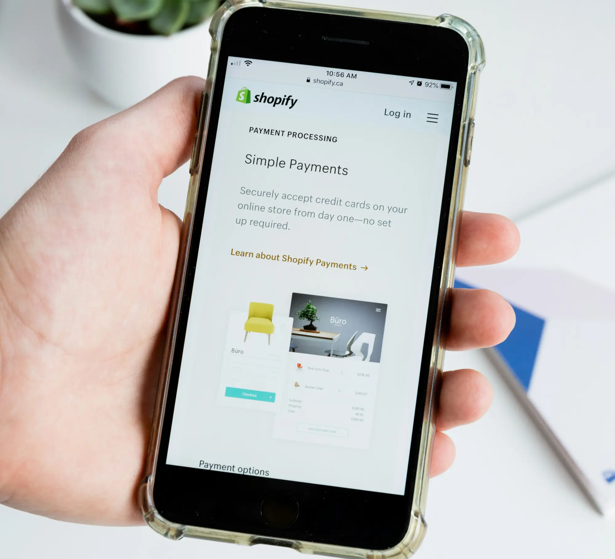 A hand holds a smartphone displaying a Shopify webpage titled Simple Payments, promoting easy credit card processing for online stores
